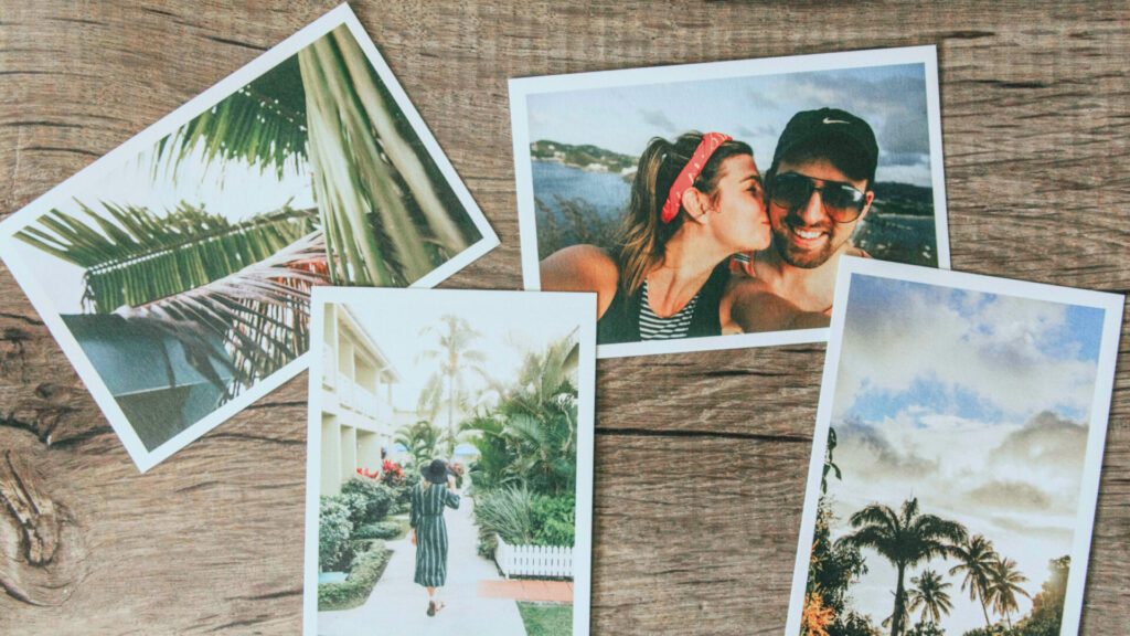 Collection of travel photos scattered on a wooden table creating a nostalgic vacation memory theme.