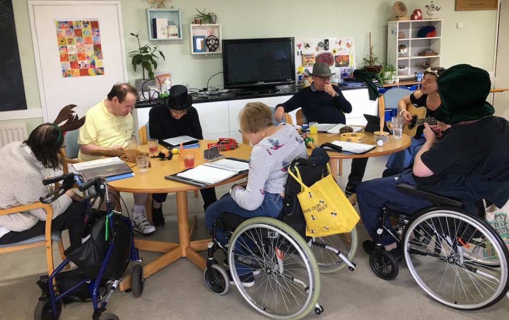 group of clients doing activities at the centre as a therapists plays guitar