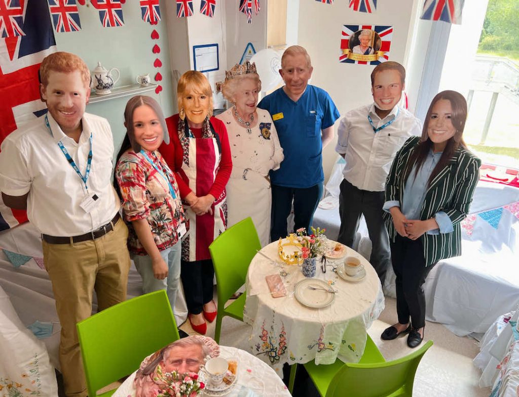 Group of people standing around a table in a decorated room with British-themed decorations
