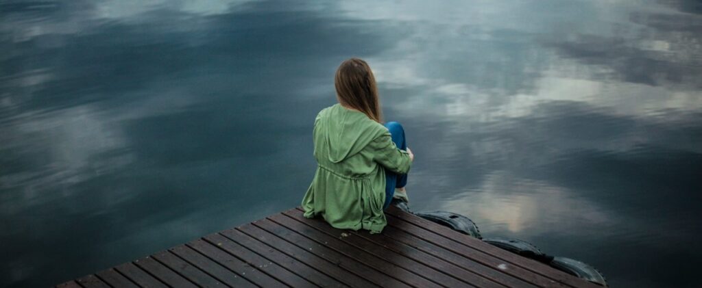 woman sitting in front of a lake